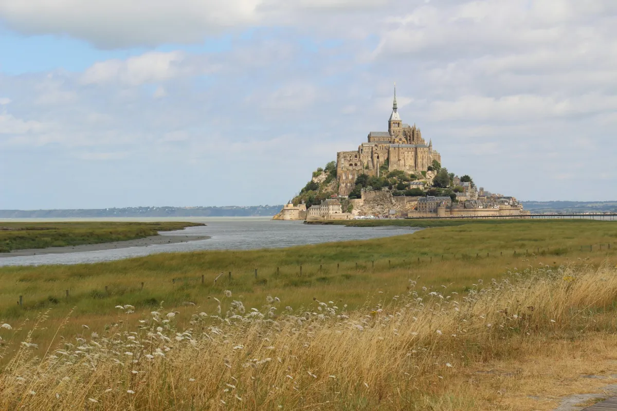 Burg auf Insel im Meer an Küste mit Dünen und Schilf im Vordergrund
