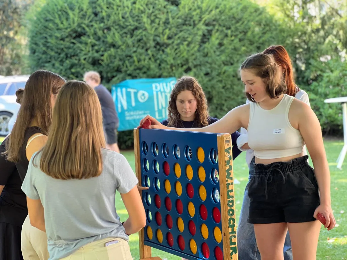 Schülerinnen spielen riesiges Vier-Gewinnt-Spiel im grünen Garten