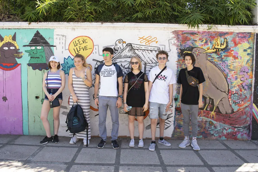 Hippe junge Austauschschüler vor Wand mit Grafitti posierend