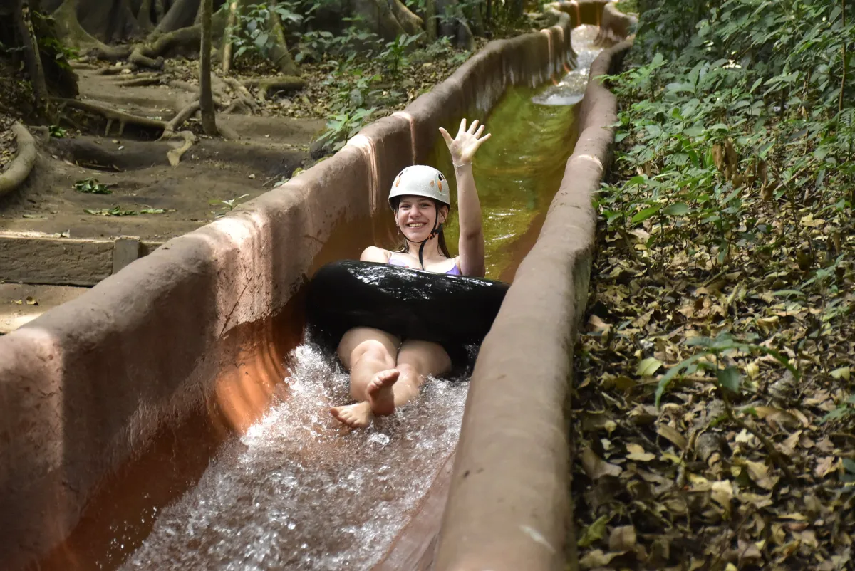 Mädchen mit Pneu auf Wasserrutsche im Dschungel 