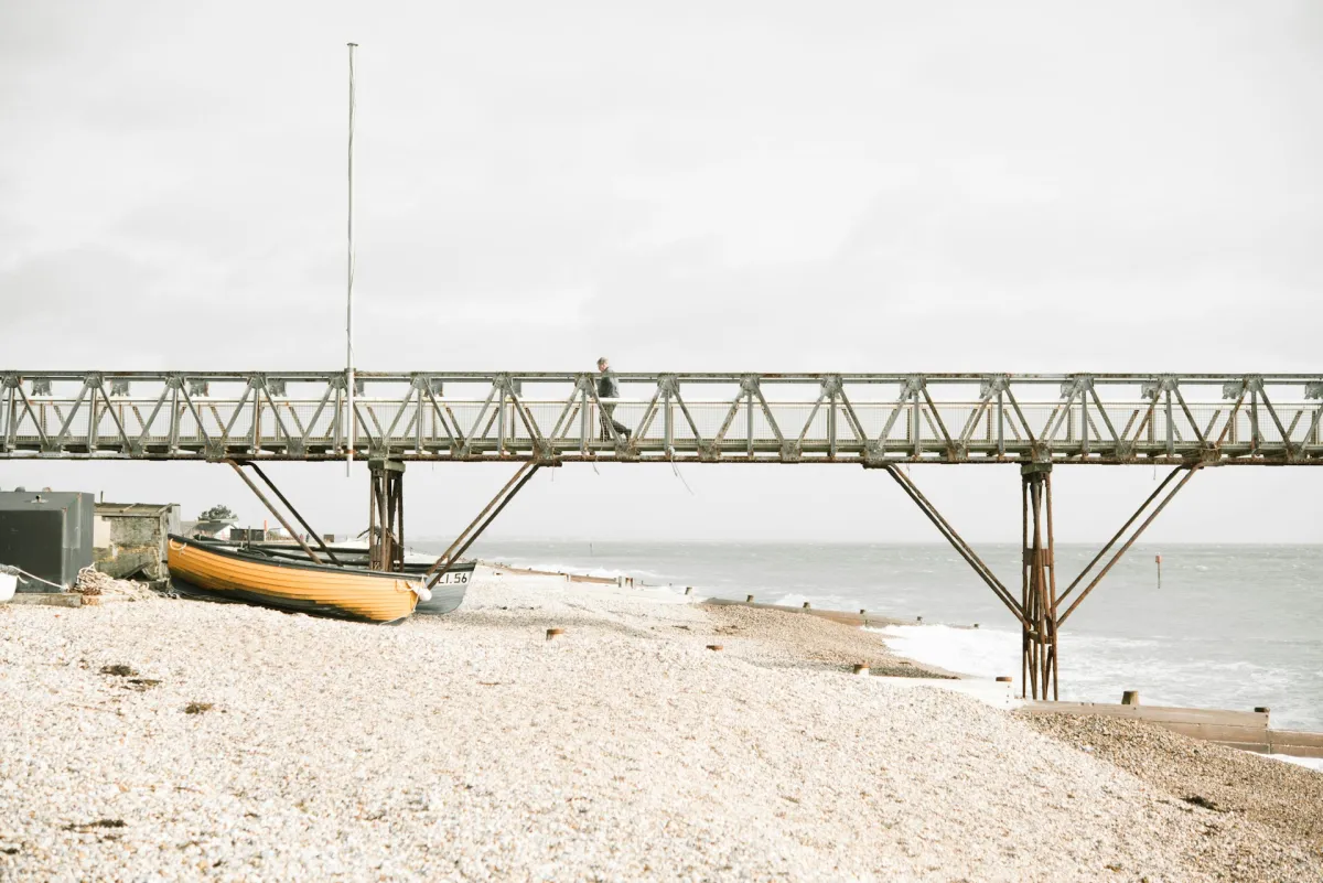 Pier über weissem Sandstrand und hellblauem Meer mit gelbem Boot darunter