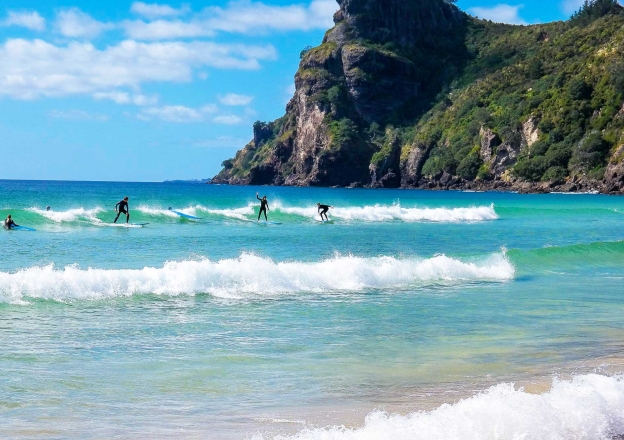 Gruppe von Austauschschüler surfen in Neuseeland an atemberaubendem Beach.