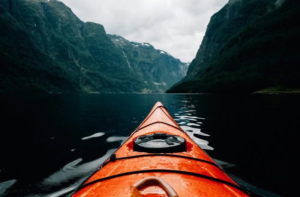 Rotes Kayak auf dunklem Wasser in norwegischem Fjord