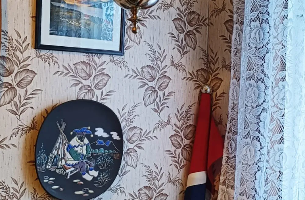 Tyisches norwegisches Wohnzimmerwand mit Flagge, Tapete, Schiffbilder und gehäkeltem Vorhang
