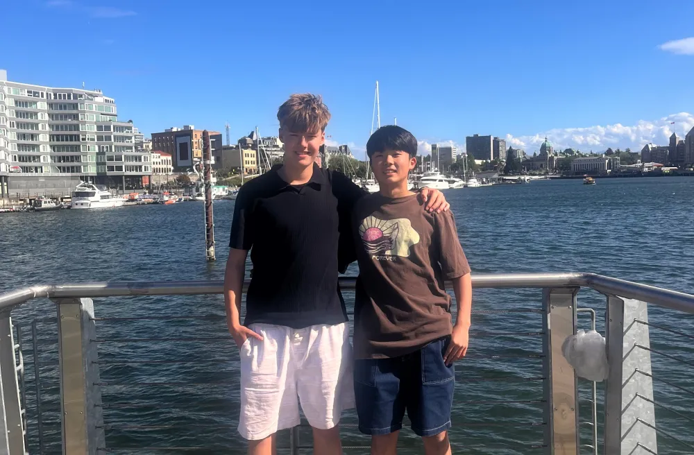 Zwei lachende Schüler stehen auf Pier vor Hafenstadt in sommerlichen Temparaturen 