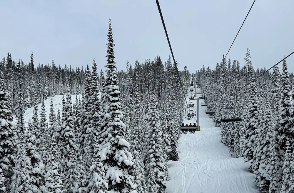 Skilift in Kanada überhalb Piste mit verschneitem Wald