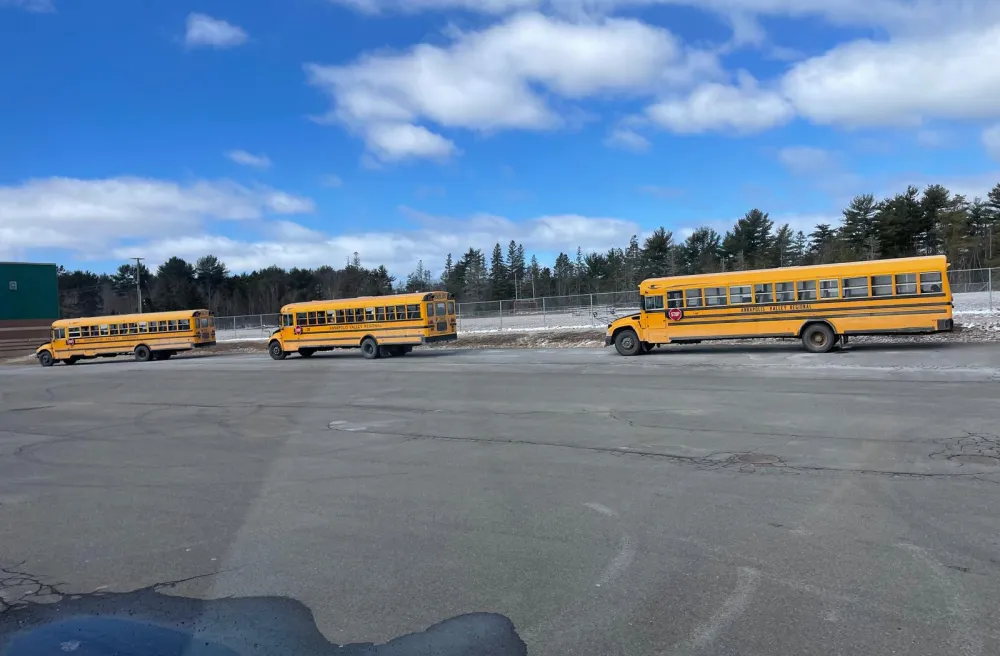3 gelbe Schulbusse fahren in Kanada unter blauem Himmel