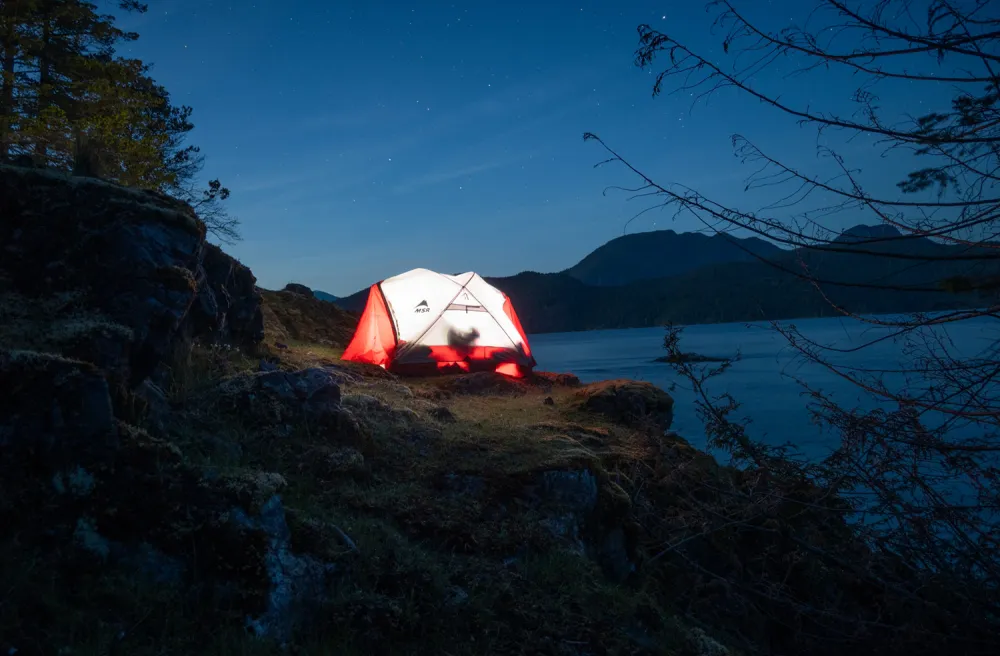 Zelt beleuchtet bei Nacht am See