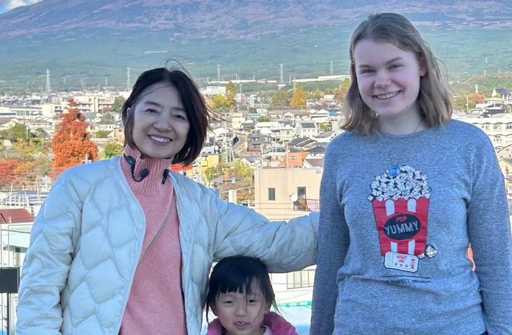 Austauschschülerin mit Gastfamilie haltend vor Mt. Fuji lachend