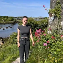 Schülerin steht auf Pfad entlang dem Meer im Grünen mit Küstenblumen