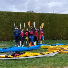 Freundesgruppe mit Paddels auf Wiese