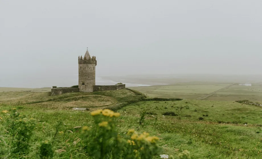 Grüne irische Landschaft im Nebel mit Schlosstrum in Wiese
