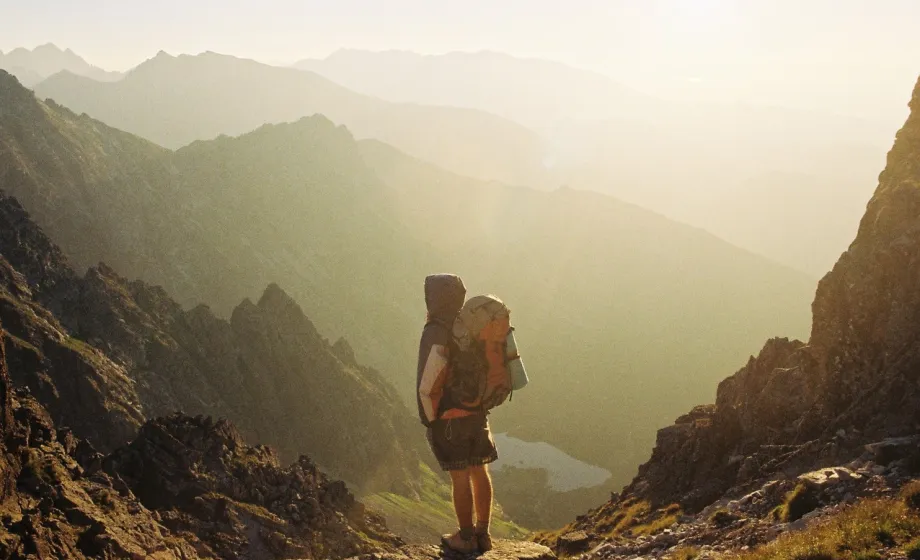 Junger Wanderer mit Rucksack in kahlem, spanischem Gebirge in magischem Sonnenlicht