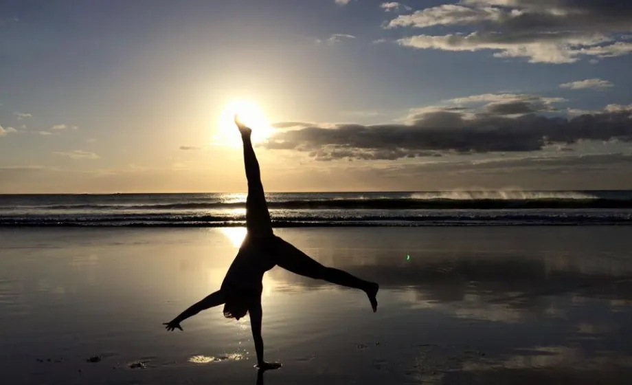 Handstand gegen die Sonne am Strand bei Sonnenuntergang