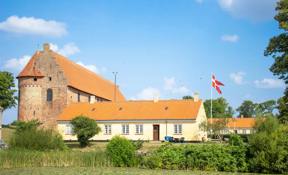 Freundliche gelbe Burg mit grünem Park ringsum und dänischer Flagge