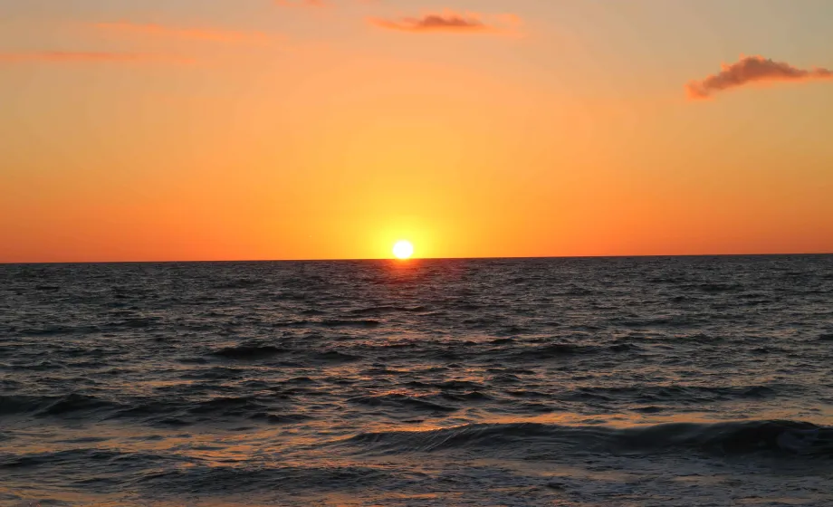 Sonnenuntergang orange über dunkelblauem Meer