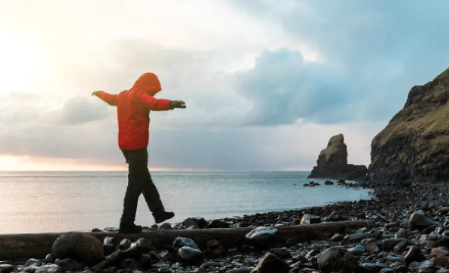 Junge balanciert auf Steinen am Strand in Schottland