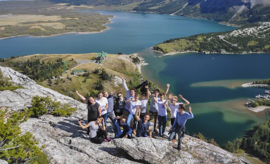 Gruppe von Schülern Arme hochhaltend auf Aussichtspunkt über Deltalandschaft